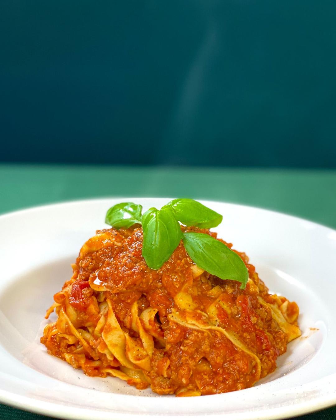 Tagliatelle al ragù sobre a toalha verde da sala
